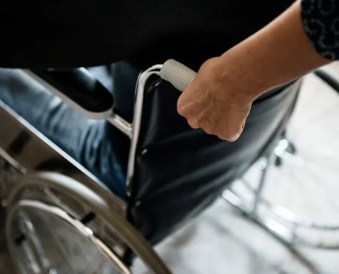 Hombre agarrando por el asa una silla de ruedas