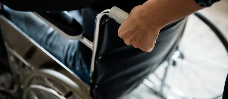 Hombre agarrando por el asa una silla de ruedas